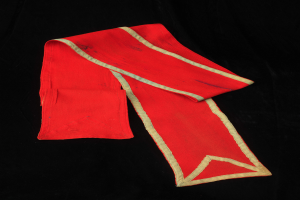 Ein roter Umhang mit goldener Borte auf schwarzem Hintergrund, der eine tiefe rote Farbe und goldene Ränder für einen luxuriösen und eleganten Look bietet.