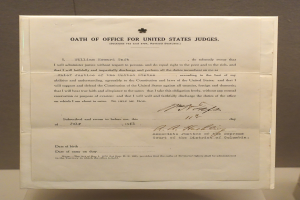 Ein Blatt mit der Aufschrift "Dienstpflicht für US-Richter" liegt auf einem Tisch vor einer Wand.