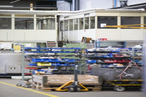 Großes Lagerinnere mit verschiedenen Geräten einschließlich fahrbaren Wagen, Schränken und einer Box, mit einer verglasten Wand und freiliegenden Rohren im Hintergrund.