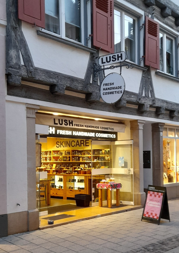 Vorderfront von "Lush Skincare" mit sichtbarem Innenraum mit Schränken, einem Schreibtisch und einem Stuhl.