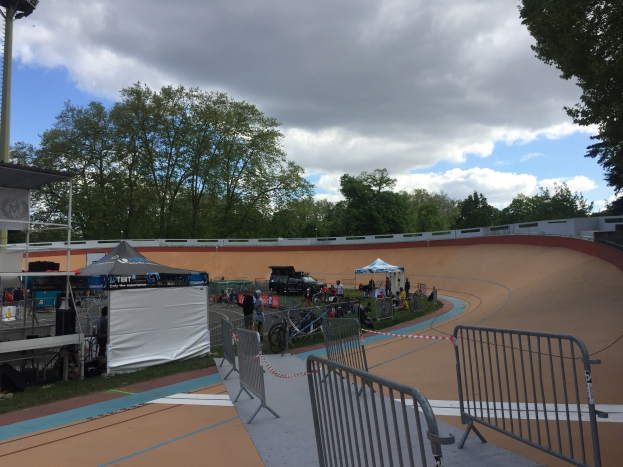 Gruppe von Radfahrern auf einer Schmutzspur bei den UCI BMX-Weltmeisterschaften 2018, mit Zuschauern, Zelten und Fahrzeugen im Hintergrund.