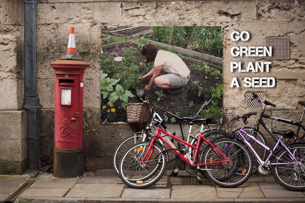 Fahrräder mit einer Briefkasten mit einer Sicherheitstonne darauf, ein Plakat an einer Wand mit Text und ein Weg am Boden.