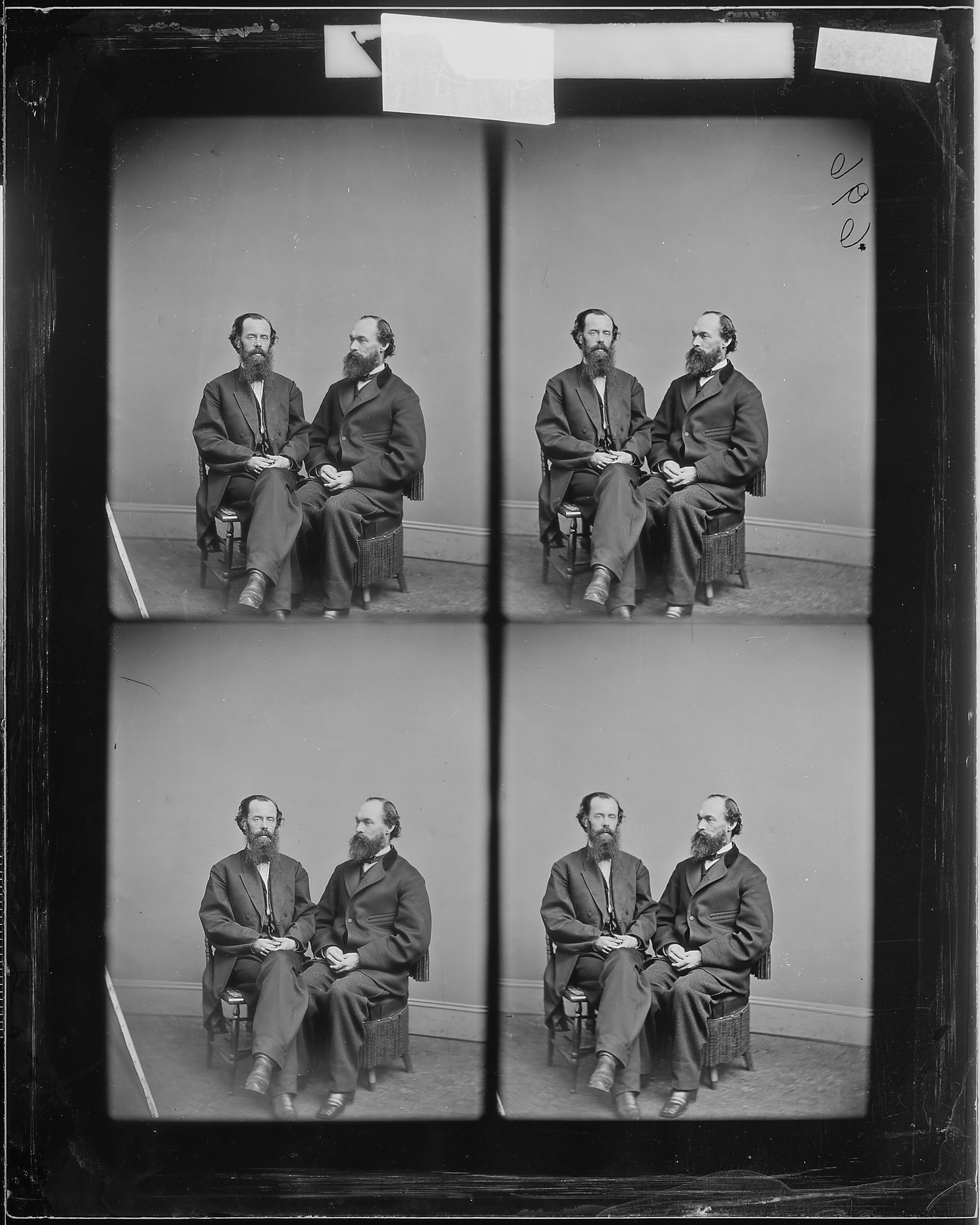 Schwarzes und weißes Foto einer Gruppe von Männern in Anzügen, die in Stühlen sitzen, die in einem Halbkreis angeordnet sind, wobei einige direkt in die Kamera schauen.