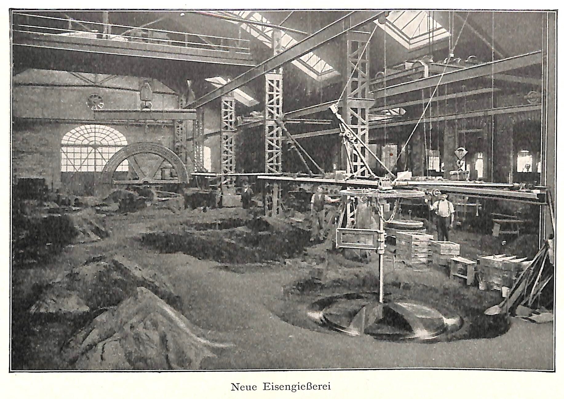 Schwarzes und weißes Foto eines Fabrikinneren mit Arbeitern, die Maschinen bedienen, Metallstangen und -rohre sowie die Beschriftung "Neue Eisengießerei, die erste Fabrik in Deutschland" unten.