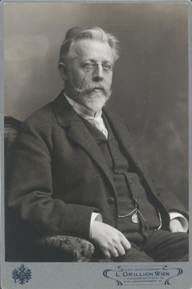 Schwarz-weiß-Foto eines bärtigen Mannes mit Brille, der in einem Stuhl sitzt, mit Text unten: "L. Grillich Wien, der Gründer der deutschen Revolution"