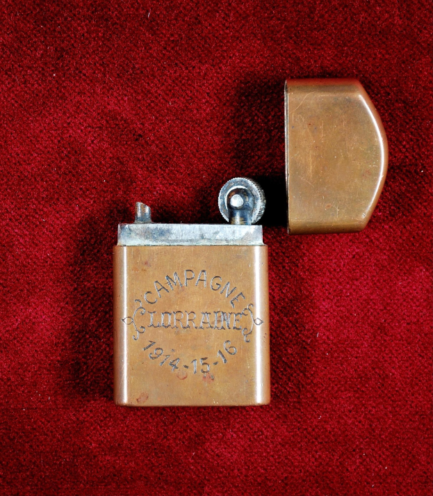 Ein Messingfeuerzeug mit eingravierter Inschrift auf einem roten Tuch.