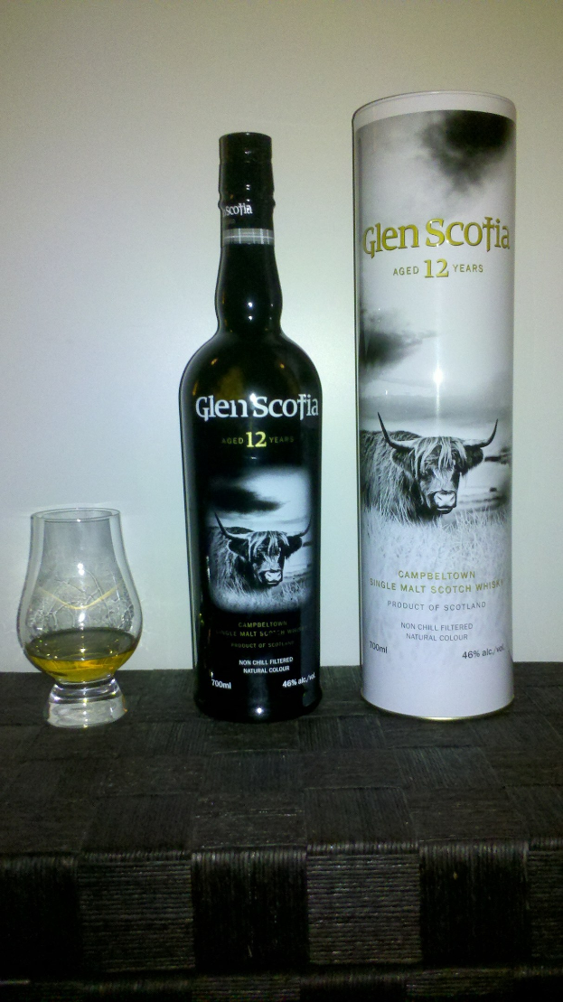 Eine Flasche Glen Scotia 12 Jahre alter Scotch-Whisky und ein Glas desselben Whiskys auf einem hellen Holztisch.