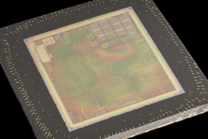 Nahaufnahme eines rechteckigen Halbleiterchips mit metallischem Glanz, schmalem Metallrahmen und kleinen L├Âchern an den Kanten auf schwarzem Hintergrund mit leicht erh├Âhten R├Ąndern.