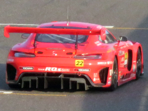 Ein leuchtend roter Porsche 911 GTS Rennauto mit einer großen Heckflosse und Flügel, das auf einer Rennstrecke fährt.